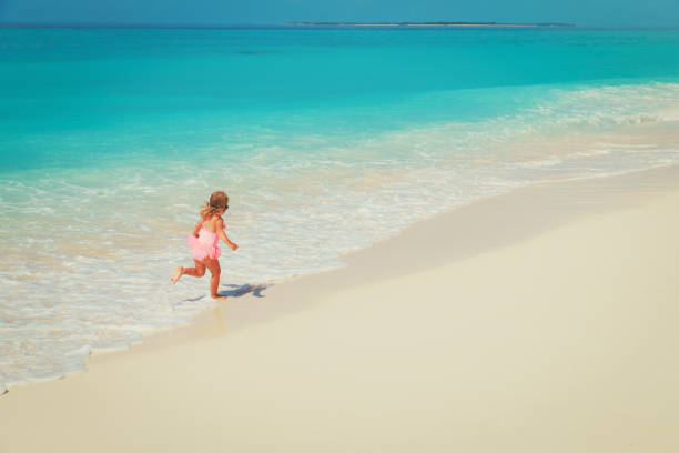 istock little girl run play with waves on beach 931243666