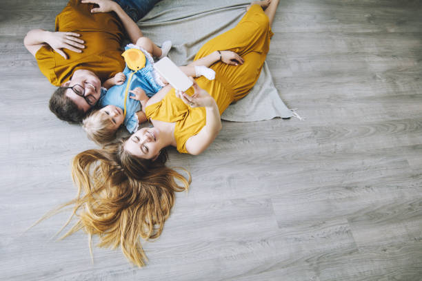 Family together happy young beautiful with little baby lying on the floor doing photo at home Family together happy young beautiful with little baby lying on the floor doing photo at home wood laminate flooring photos stock pictures, royalty-free photos & images