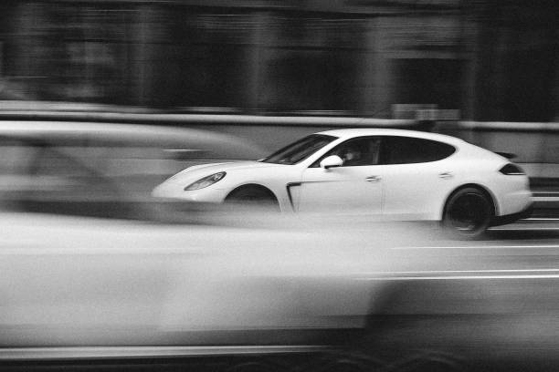White Porsche Panamera in Motion Minsk, Belarus - April 15, 2017: White Porsche Panamera in Motion at Intensive Traffic on Independence Avenue. Speed. Motion blur shot. Editorial Black and White photo. minsk photos stock pictures, royalty-free photos & images