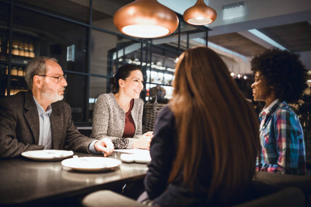 Businesspeople sitting in restaurant and having meeting Businesswoman, creative team leader and her multi-ethnic team on the meeting in a high end restaurant business dinner stock pictures, royalty-free photos & images