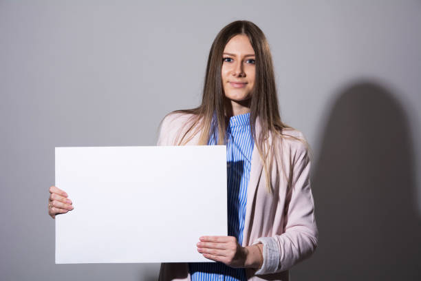 istock Young beautiful woman in a jacket with blank sheet 931261840