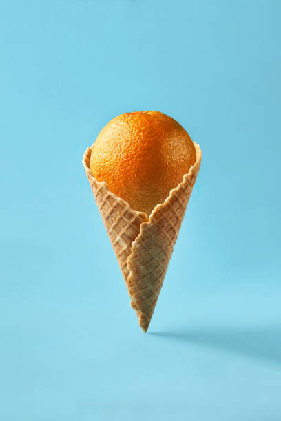 istock Orange like ice cream lies in waffle cone on a light blue background 931263630