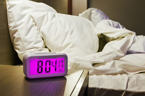 electronic alarm clock stands on a bedside table in the room or hotel room