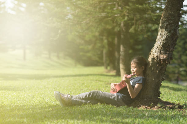 istock Girl Playing Guitar While Sitting On Grassy Field At Park 931283226