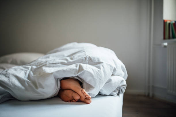 sección baja de mujer joven durmiendo en la cama - sheet sleeping women bed fotografías e imágenes de stock