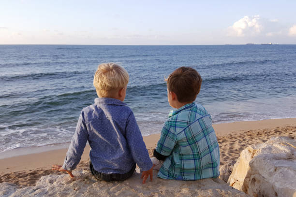 istock Two children, little brothers sitting seashore 931284034
