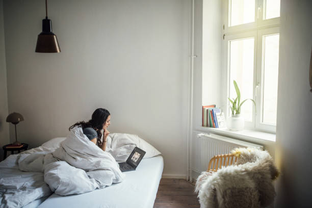 Young woman using laptop on bed at home