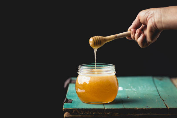 istock Honey in a glass bottle On blue wood in low light 931290774
