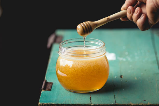 istock Honey in a glass bottle On blue wood in low light 931290954