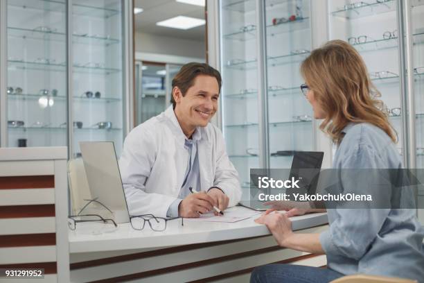 Doctor Alegre Hablar Con El Cliente Foto de stock y más banco de imágenes de Optometrista - Optometrista, Tienda - Lugar de comercio, Optometría