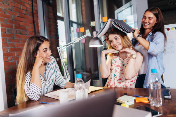 istock Three funny young students having fun while sitting at desk preparing for exam in study room 931323894