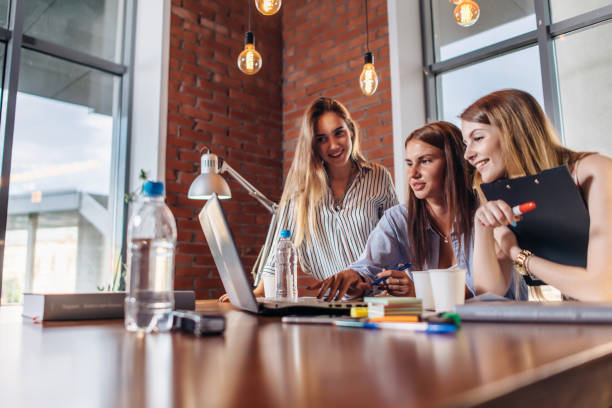 istock Three positive businesswomen working on laptop discussing joint business project 931324356
