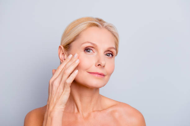 pretty, charming, attractive woman touching, enjoying her perfect face skin, holding fingers on cheek, pimple, whelk, pustule, dry, oiled, problem skin concept, isolated on grey background - moisturizer women cosmetics body imagens e fotografias de stock