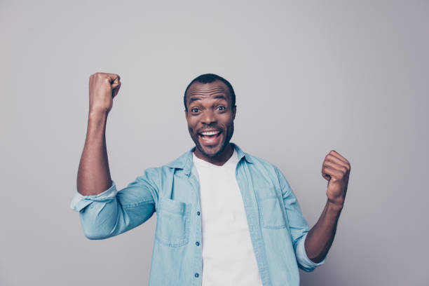 portrait of positive, happy, shouting, screaming, laughing man with open mouth and raised arms, celebrating successfully completed work, isolated on grey background - ecstatic excitement arms raised men imagens e fotografias de stock