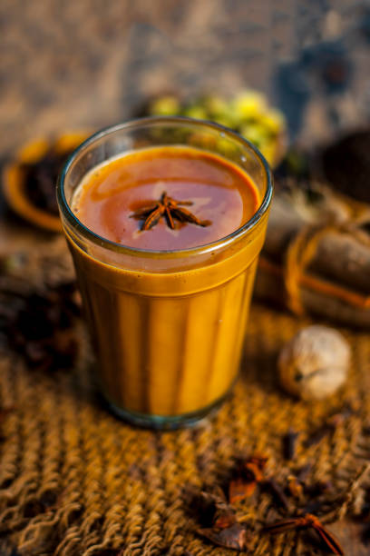 Close up of popular Indian/Asian drink " 
Masala Chai" or Spicy tea/normal tea with all the ingredients including sugar on a wooden surface. stock photo