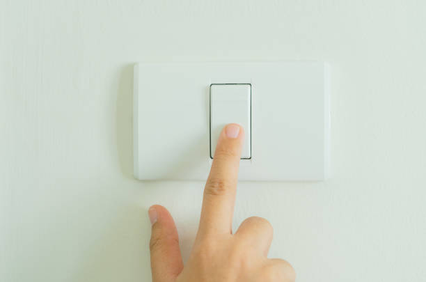 istock Close up of finger turning off on light switch on wall. 931339674