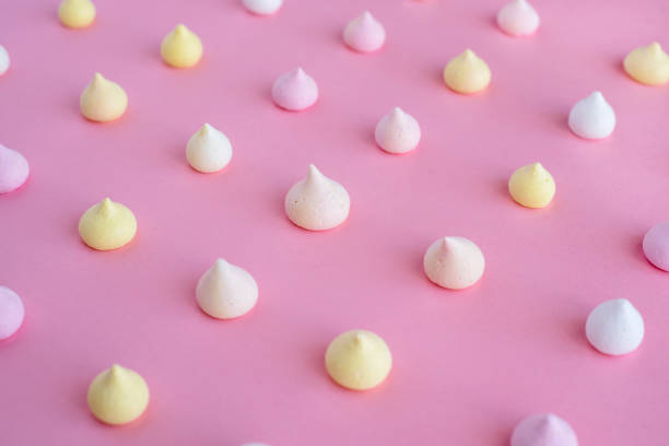 istock Multicolored meringue arranged in an even row on a pink background 931347054