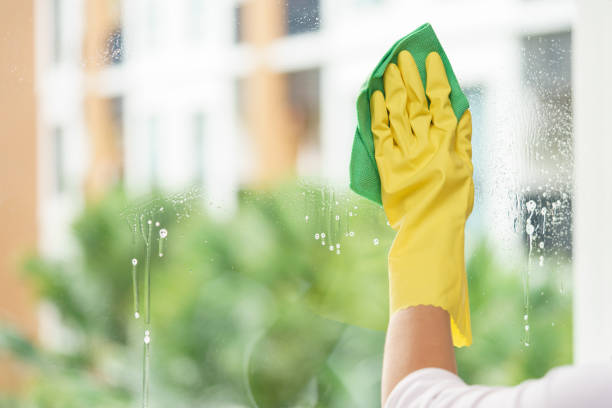 Woman housekeeper cleaning the mirror with green cloth stock photo