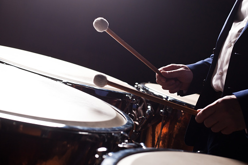 The hands of a musician playing on a timpani