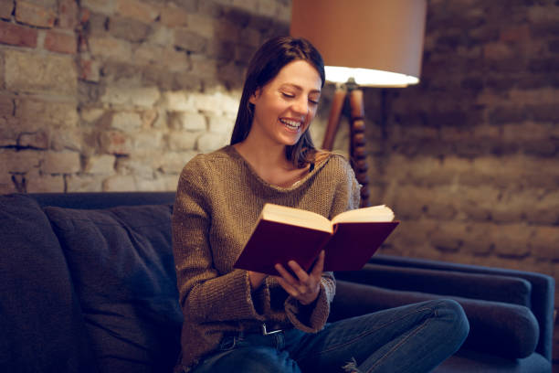 istock Young woman sitting on sofa reading a book 931358130