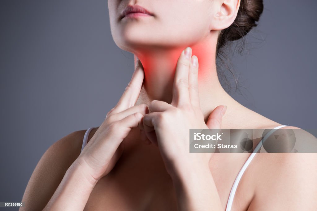 Sore throat, woman with pain in neck, gray background Sore throat, woman with pain in neck, gray background, studio shot Thyroid Gland Stock Photo
