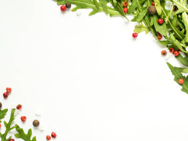 istock Frame of green arugula leaves with red and black pepper white background copy space 931375756