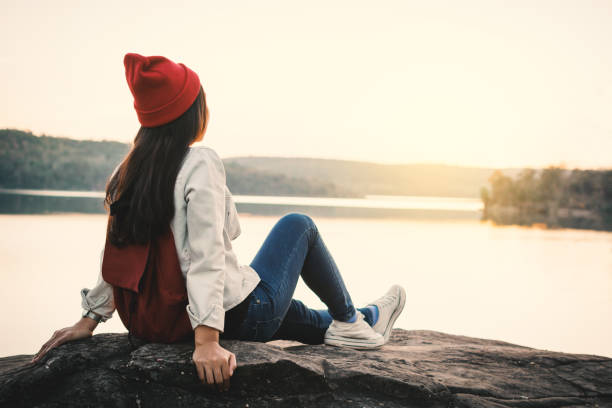 istock Woman With Backpack Sitting By Lake Against Clear Sky 931380348