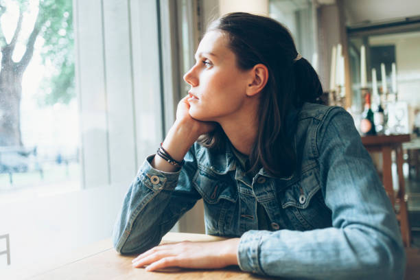 Pensive young woman sitting in cafe alone