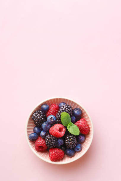 Berry (raspberry, blueberry, blackberry) fruits bowl on a pastel background. Top view. Copy space stock photo