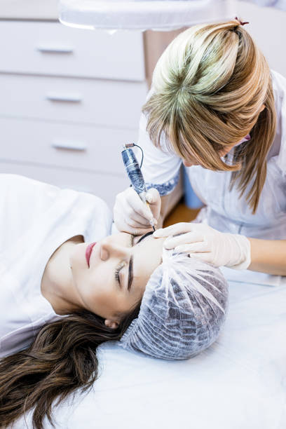 istock Beautician female applies permanent makeup on eyebrows, tattoo eyebrows on beautiful models in a beauty parlor 931403436