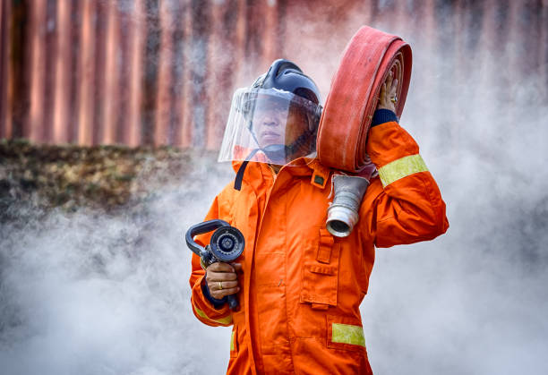 istock Emergency Fire Rescue training, firefighters in uniform,  carry a water hose run through flame 931408054