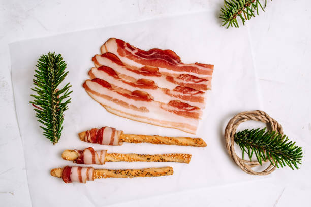 istock Top view of sliced bacon wrapped around pretzels on white background. 931409516