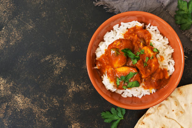 chicken korma mit pikanter sauce auf weißem reis. traditionelles indisches gericht auf einem rustikalen hintergrund. ansicht von oben, raum zu kopieren. - curry sauces stock-fotos und bilder