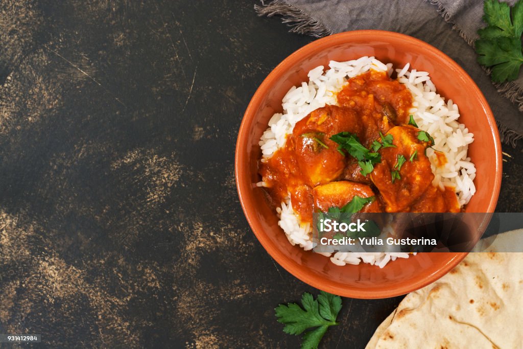Chicken korma with a spicy sauce over white rice.Traditional Indian dish on a rustic background. Top view, copy space. Chicken korma with a spicy sauce over white rice.Traditional Indian dish on a rustic background. Top view, copy space Indian Food Stock Photo