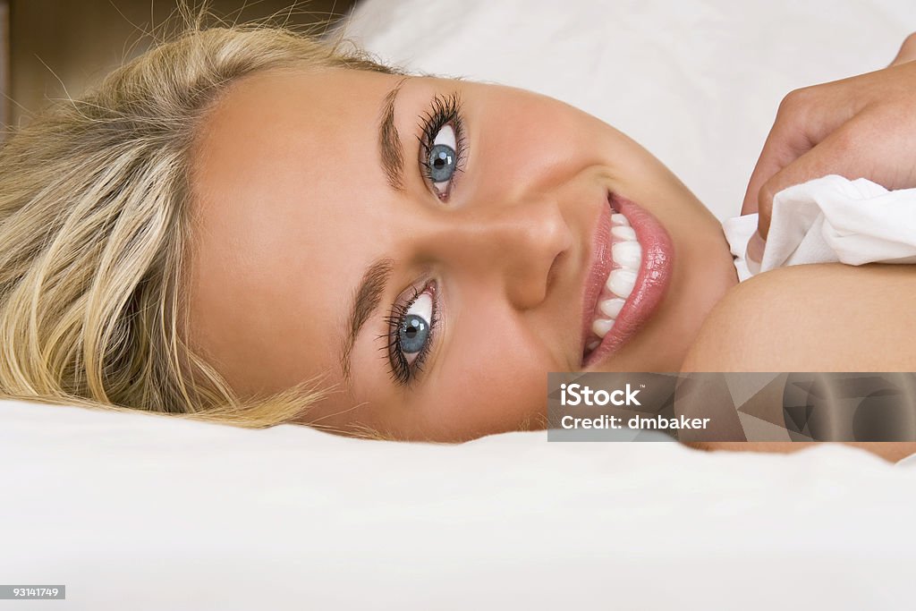 Bela loiro mulher sorridente na cama segurando uma folha - Royalty-free Acordar Foto de stock