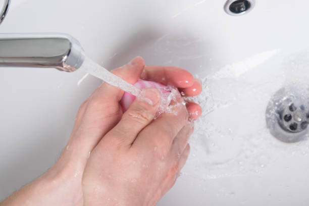 istock under a stream of water with pink soap, hands are soaped up 931428384
