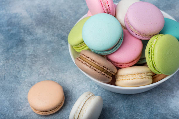 istock Colorful makarons in a white plate on a blue background. Copy space 931428976