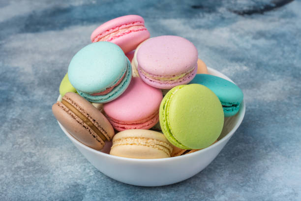 istock Colorful makarons in a white plate on a blue background. Copy space 931429054