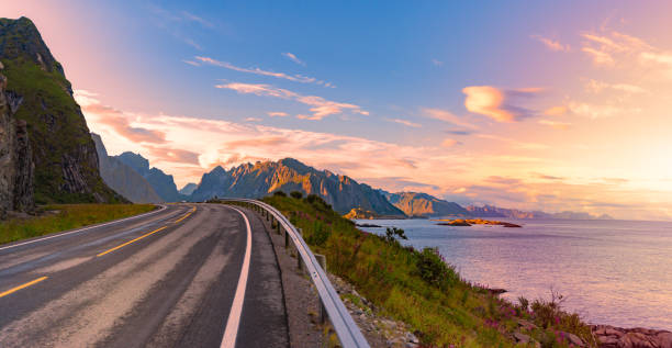 Panorama of empty winding country road in Norway, Europe, Scandinavia. Auto travel on sunset. Blue sky with clouds and mountains. Lofoten islands. Panorama of empty winding country road in Norway, Europe, Scandinavia. Auto travel on sunset. Blue sky with clouds and mountains. Lofoten islands. northern norway stock pictures, royalty-free photos & images