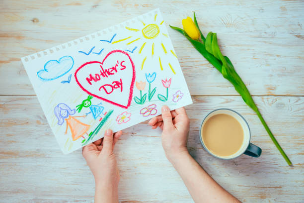 istock mother look on kid picture with mother day congratulation while drink coffee. overhead view 931445772