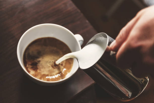 istock man pouring into a cup of coffee with milk 931449006