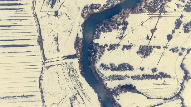 istock Aerial view riverbend passing snow covered fields. 931458588