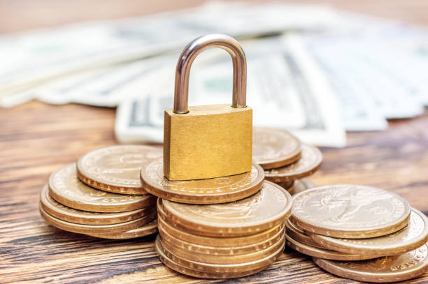 istock Padlock with coins and dollar bills on the table. 931461392