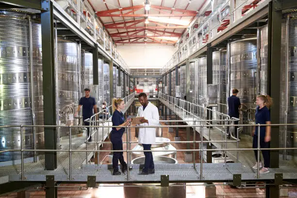 Two staff talking on gangway in a modern winemaking factory