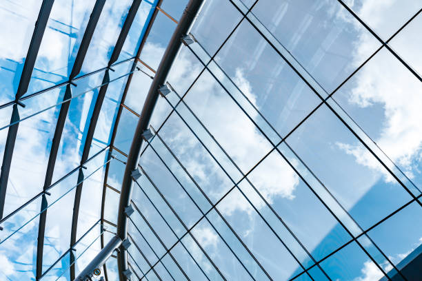 New modern building with glass roof looking up through glass house ceiling looking beautiful cloudy and sunny blue sky on spring day