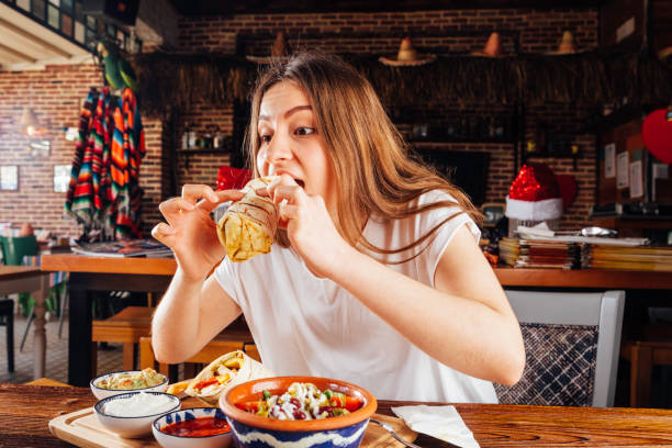 istock Young woman eating burrito for lunch 931470398
