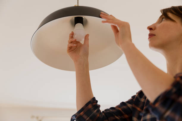 mujer de reemplazar el foco en el país. cambio de lámpara de led de ahorro de energía - compact fluorescent lightbulb fotografías e imágenes de stock