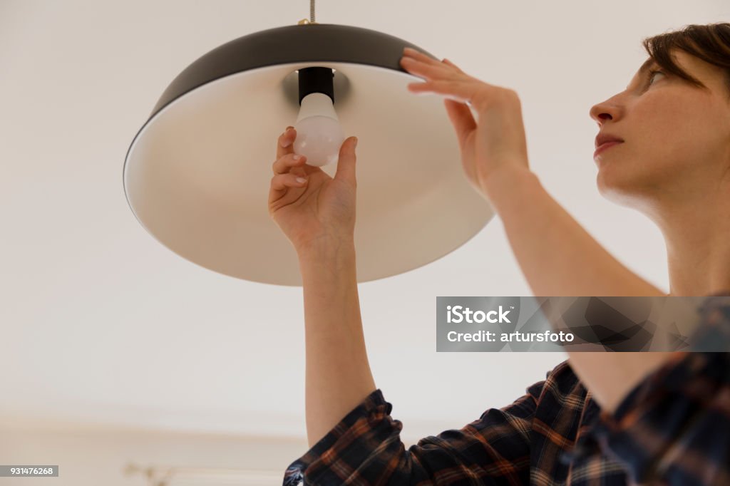 Woman replacing light bulb at home. Power save LED lamp changing Light Bulb Stock Photo