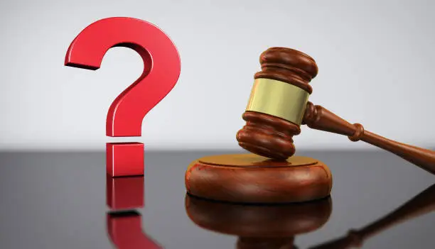 Law and legal questions concept with a red question mark sign and a wooden judge gavel on a desk with grey background 3D illustration.