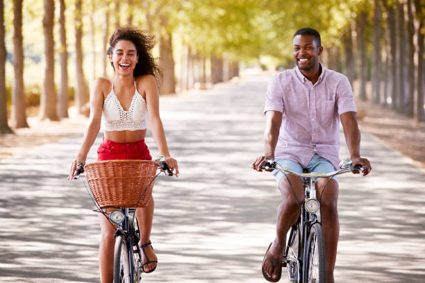 istock Young mixed race couple riding bicycles on a tree lined road 931476610